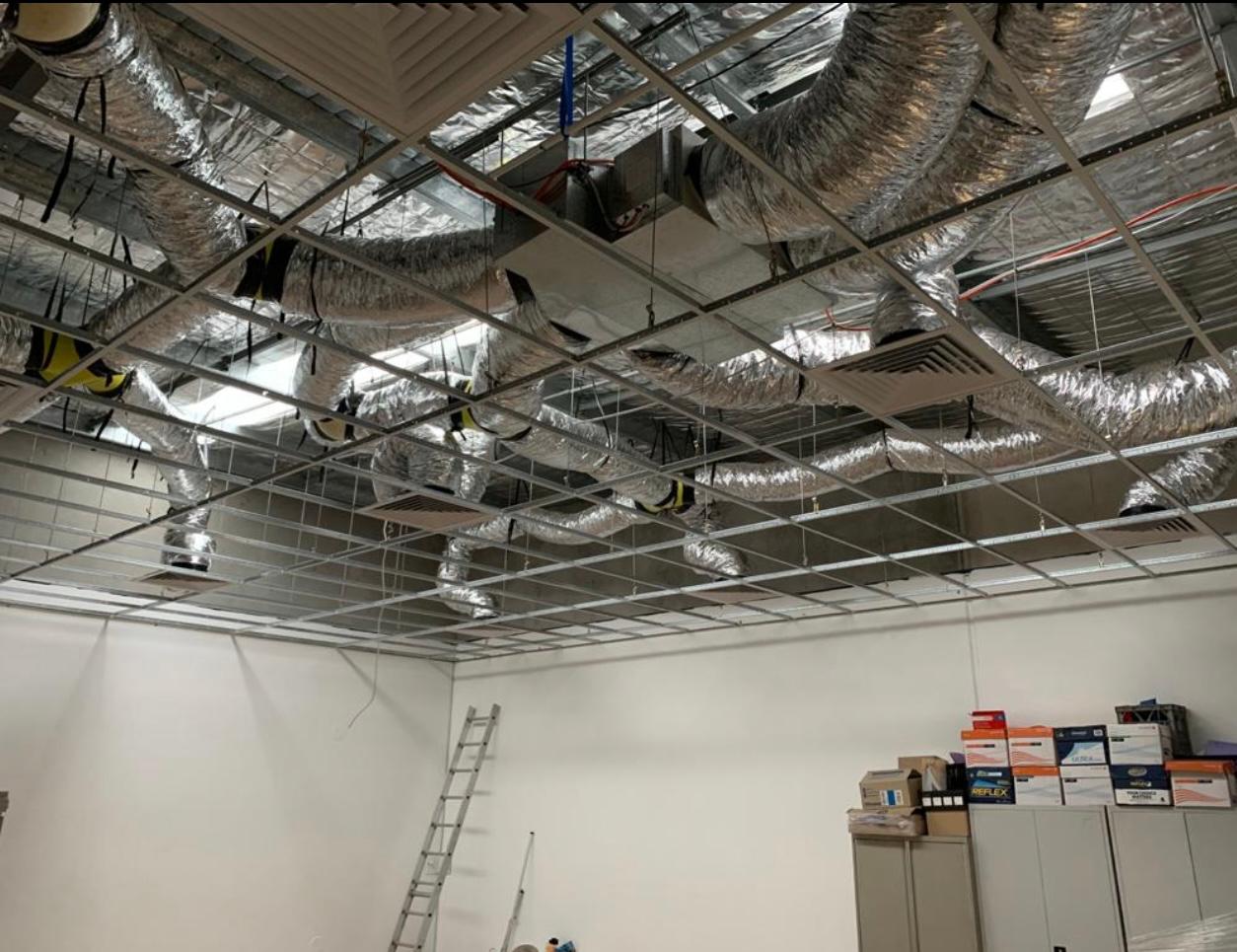 Commercial ducted air conditioning installation by Toptech Air — silver flexible ductwork routed through a suspended ceiling grid in a Sydney commercial space